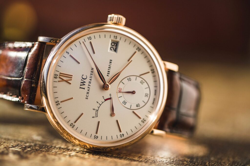 IWC Portuguese and Portofino - a Portofino with gold case, cream dial, and leather band